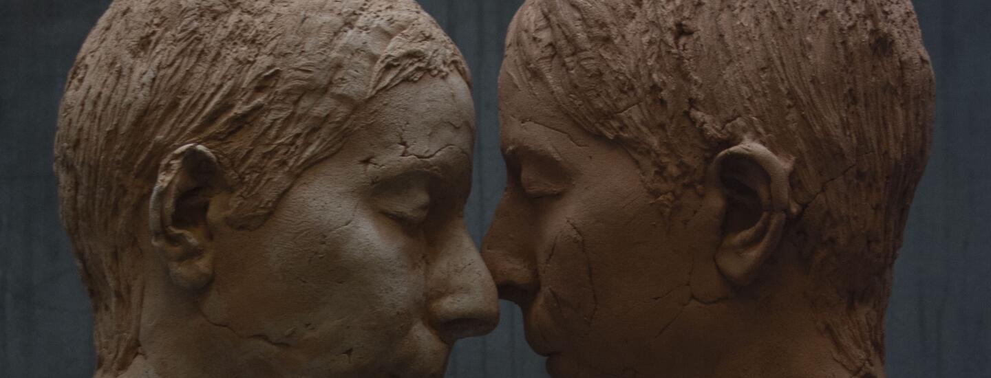 closeup of two sculptural faces in profile with faces touching