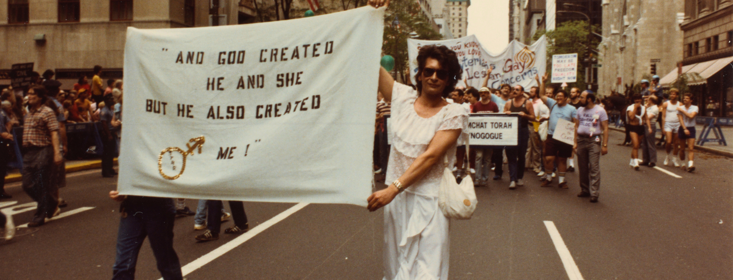 Archival image of Sylvia Rivera walking in a protest holding a large banner 