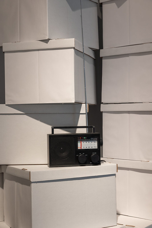 A black radio sits on top of white archival boxes.