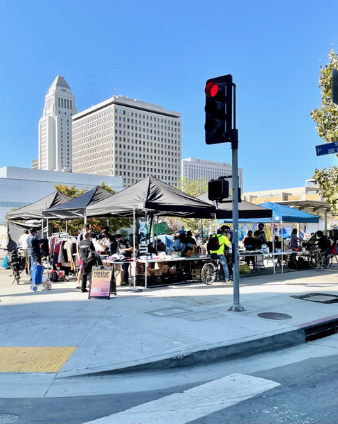 Photograph of a street corner with a sign that says POWER UP along with tents and people gathered 