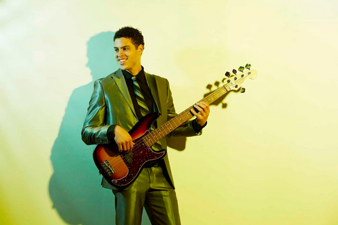 Jonathan holds a bass against a yellow background