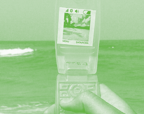 Photo in green scale of a hand holding a retro cell phone