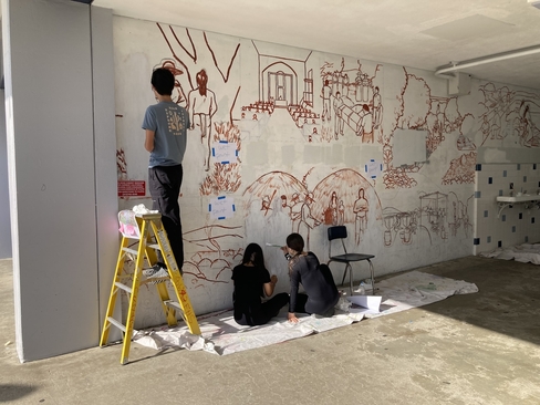 three students with their backs to the camera work on the in-progress Franklin Mural