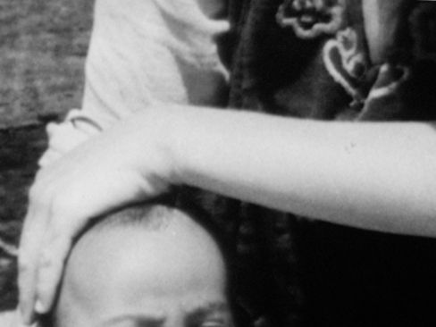 Still from the film Via Dolorosa by Oraib Toukan, abstract archival shot of a person's head and another person's arm