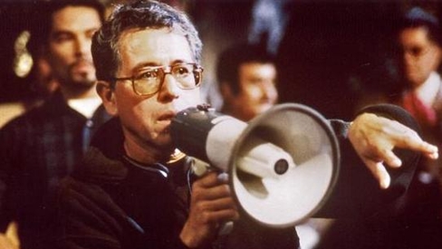 Jesús Salvador Treviño Directing Resurrection Blvd. Jesús wears glasses and stands with a megaphone, speaking to someone outside of the image frame. 