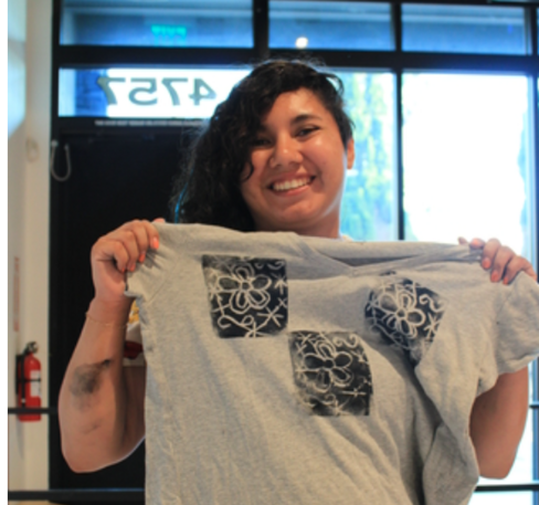 Photo of a person holding up a shirt and smiling. 