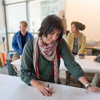 Artist Liz Collins works at a drafting table for her installation Knitting Nation