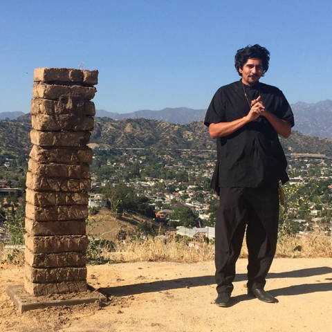 Artist Rafa Esparza stands next to one of the pieces in his interactive installation HERE