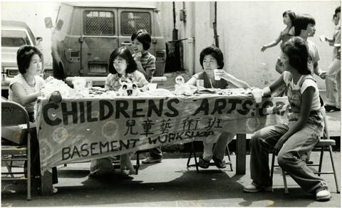 Table set up outdoors with a banner and several people sitting around the table.