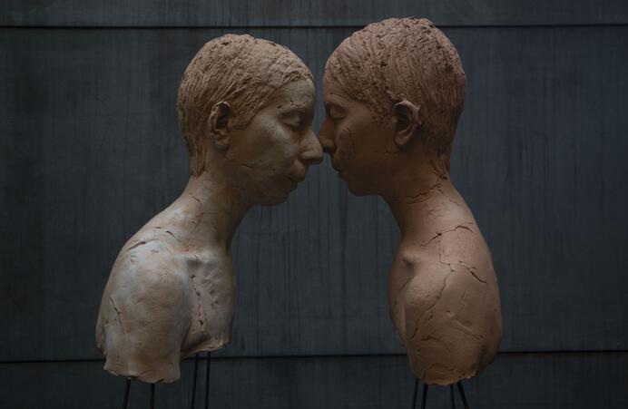 color image of two sculptural busts in profile, with their faces touching