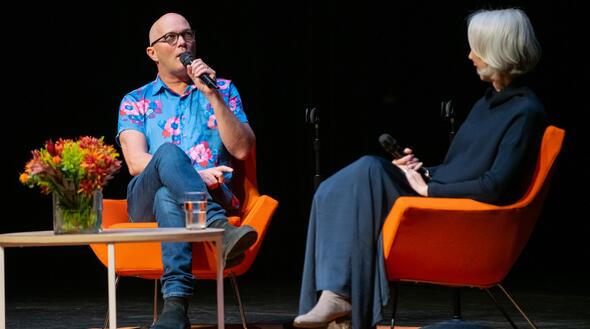 color image of Taylor Mac on stage in conversation with Alexandra Grant